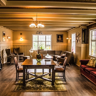En stor stue med sofagrupper og spisebord med hyggelig atmosfære på Valldal Fjord Lodge