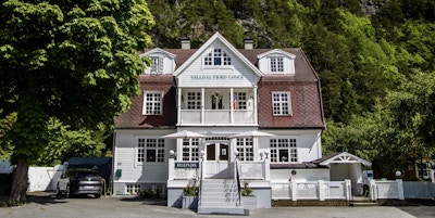 Et hvitt trehus i gammel stil er hovedhuset på Valldal Fjord Lodge