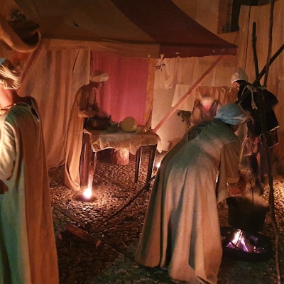 5 personer i middelalderdrakter i aktivitet inne i et telt