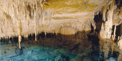 Inne i en grotte med dryppstein, vann og formasjoner