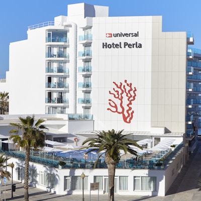 Hotellfasade med balkonger som ser utover et basseng og palmer