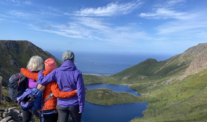 Tre damer nyter utsikten over fjellene mot havet fra Dronningruta