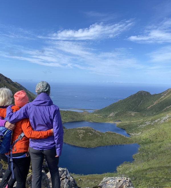 Tre damer nyter utsikten over fjellene mot havet fra Dronningruta