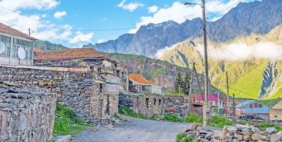 Det gamle nabolaget i Stepantsminda resort, som ligger rett ved fjellfoten og i skråningen, består av steinhusene, Kazbegi, Georgia.