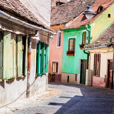 Gamle fargerike hus og hytter i brosteinsbelagte gate, Sibiu, Transylvania, Romania. Sibiu er en by i Transylvania, Romania, med en befolkning på 147.245. Hotellet ligger omtrent 215 km nordvest for Bucuresti, og ligger rundt Cibin-elven, en sideelv til elven Olt. Nå var hovedstaden i Sibiu County, mellom 1692 og 1791 og 1849-1865 Sibiu hovedstad i fyrstedømmet Transylvania. Horisontalt fargebilde med kopieringsplass.