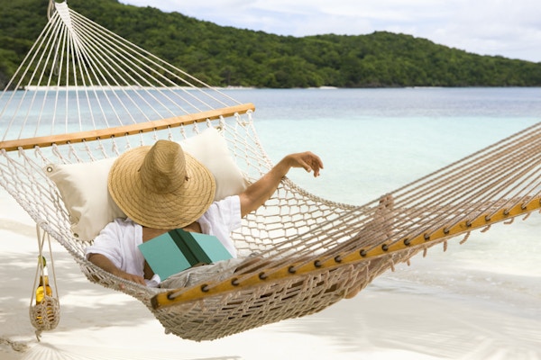 En mann som hviler i hengekøye på den karibiske stranden