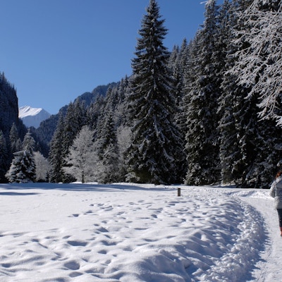 Vinter i skog og fjell og to personer som er ute og går tur