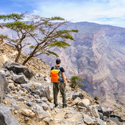 En turgåer nyter utsikten over canyonen i Jebel Shams-fjellet i Oman