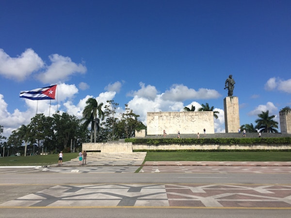 Monument utenfor Mausoleumet til Che Guevara i Santa Clara, Cuba med cubansk flagg som vaier i vinden foran palmer og blå himmel