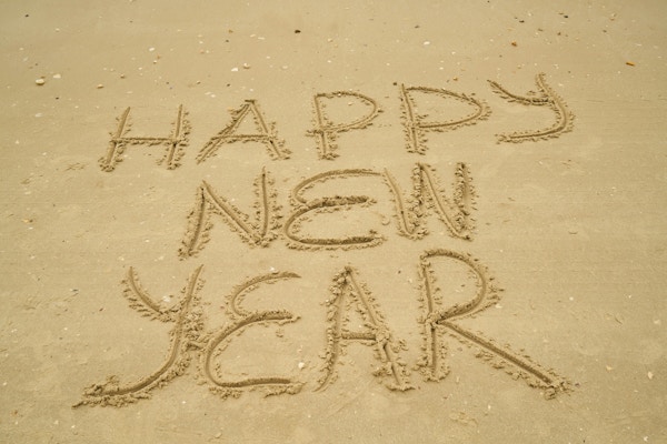 Teksten godt nytt år på engelsk skrevet i sanden på en strand
