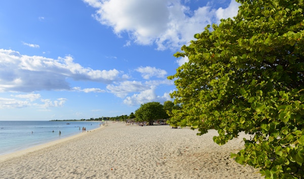 En utsikt over den karibiske stranden ved Playa Ancon, med folk i bakgrunnen. Playa Ancon ligger flere kilometer fra Trinidad, i Sancti Spiritus-provinsen, Cuba.