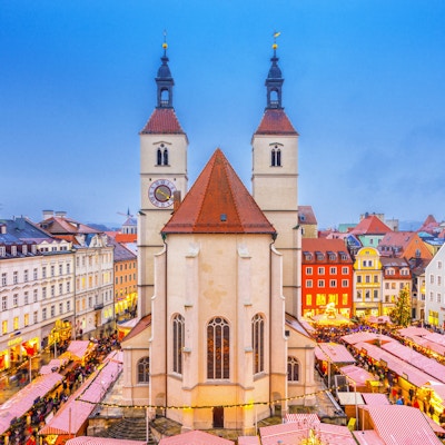 Forhøyet utsikt over Regensburgs julemarked med mat og julepyntboder rundt den 500 år gamle Neupfarr-kirken og vakre byhus.